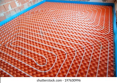 Installation of underfloor heating- orange panels and white plastic pipes.