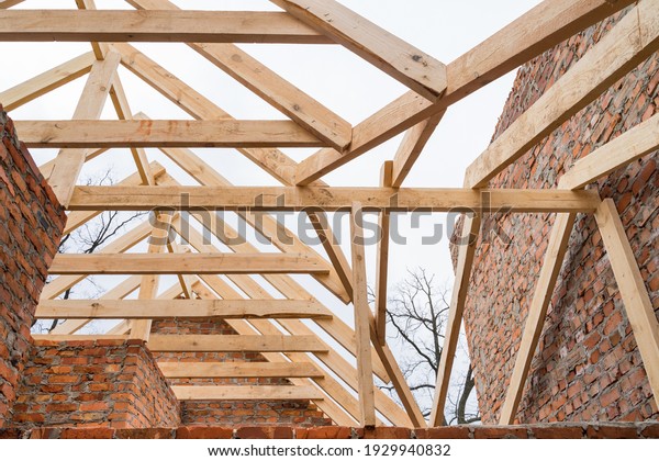 Installation of wooden beams at construction the\
roof truss system of the brick\
house.