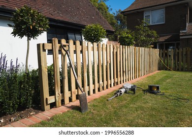 The Installation Of A Wooden, Natural Wood Colour, Picket Fence In A Residential Garden. 