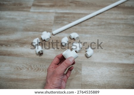 Installer Checks Connection. PVC Coupling Attachment Demonstration. Illustration Of Plumbing Component Assembly Process. Hand Positioning PVC Joint During Installation On Wooden Surface