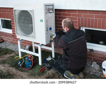 The installer installs the heat pump in a single-family house - Shutterstock ID 2099389627