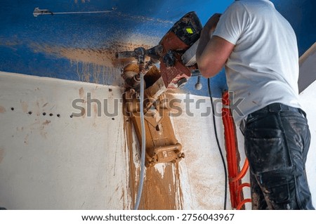Installer presses a drill rig into the ceiling to enlarge an opening for ventilation connection, while wet drilling residue runs down the wall in the work area.