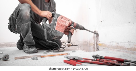 Installer stabs hole with Hilti rotary hammer in the wall on the construction site