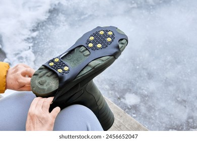 Installing anti slip shoe grips with cleats on bottom of boot. - Powered by Shutterstock