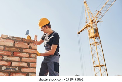 Installing Brick Wall. Construction Worker In Uniform And Safety Equipment Have Job On Building.