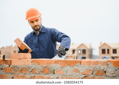 Installing brick wall. Construction worker in uniform and safety equipment have job on building.