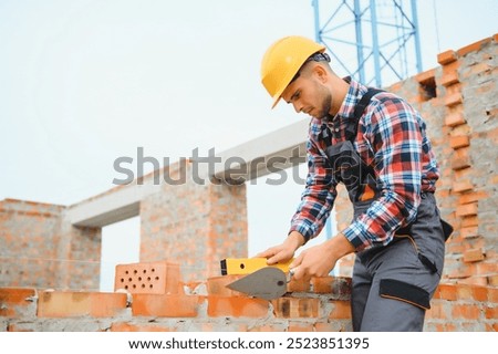 Installing brick wall. Construction worker in uniform and safety equipment have job on building.