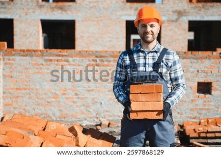 Installing brick wall. Construction worker in uniform and safety equipment have job on building.