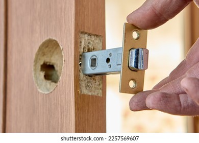 Installing door latch in slot of interior door. - Shutterstock ID 2257569607