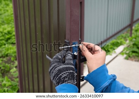 Installing a door lock. The worker selects a bolt for the door lock.