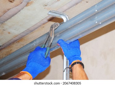 Installing Garage Door Opener Mechanism. Contractor Installing Garage Door Tracks And Mounting Hardware.