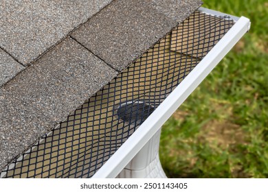 Installing gutter guard mesh screen on rain guttering. Home maintenance, yardwork and roof damage concept