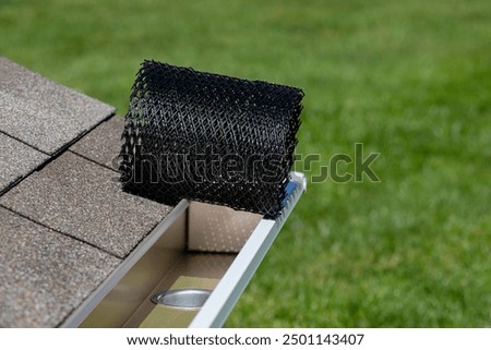 Installing gutter guard mesh screen on rain guttering. Home maintenance, yardwork and roof damage concept