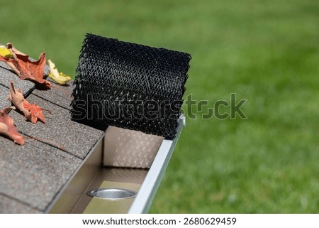 Installing gutter guard mesh screen on rain guttering. Home maintenance, yardwork and roof damage concept