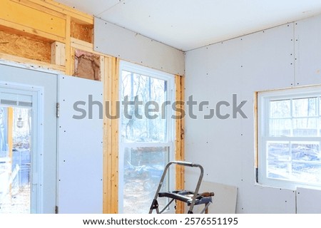 Installing gypsum drywall in space for improved energy efficiency through large windows.