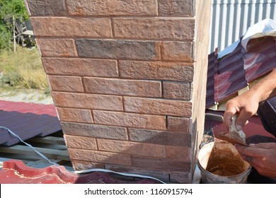 Installing house chimney blocks on the rooftop. Roofer decorate and protecting chimney bricklaing.