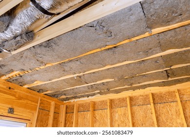 Installing insulation between exposed beams in wooden structure for improved energy efficiency during construction new house