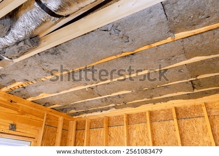 Installing insulation between exposed beams in wooden structure for improved energy efficiency during construction new house