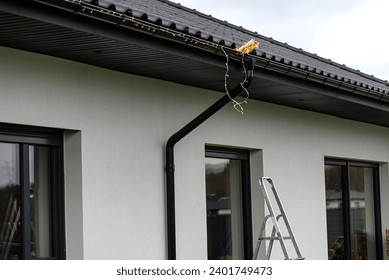 Installing LED lights along the gutter around the house, decorating the house for the holidays.