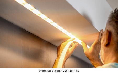 Installing led strip for lighting correctly on the surface of the Cabinet on the kitchen set.