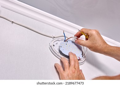 Installing LED wall light fixture, electrician connect connecting wires to home electrical wiring. - Powered by Shutterstock