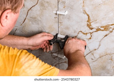Installing leveling system tiles using black tongs.