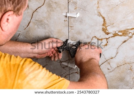 Installing leveling system tiles using black tongs.