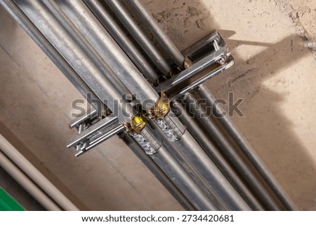 Installing metal electrical conduit inside a building, on a concrete ceiling.