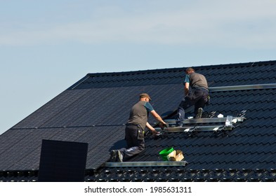 Installing new black solar panels on the metal roof of a private house. Ecology, renewable energy and green sustainable source of power abstract. - Shutterstock ID 1985631311
