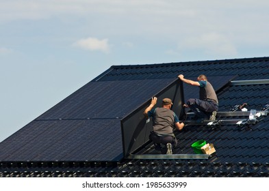 Installing New Black Solar Panels On The Metal Roof Of A Private House. Ecology, Renewable Energy And Green Sustainable Source Of Power Abstract.