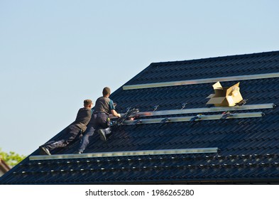 Installing new black solar panels on the metal roof of a private house. Ecology, renewable energy and green sustainable source of power abstract. - Shutterstock ID 1986265280
