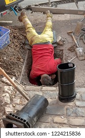 Installing A New Water Meter In The Road. UK. Man Leaning Into A Hole To Make The Installation