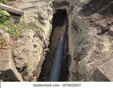 Installing Sewer Pipe In The Ground Trench. House Sewer Drain Pipe Installation