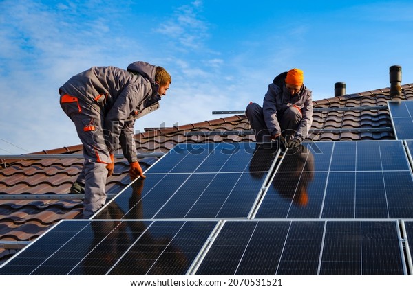 Installing a\
Solar Cell on a Roof. Solar panels on roof. Workers installing\
solar cell farm power plant eco\
technology.