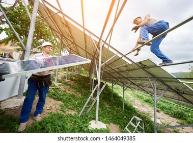 Installing of solar photo voltaic panel system. Three technicians lifting heavy solar module on high platform. Investment in alternative energy, money saving and professional construction concept. - Shutterstock ID 1464049385