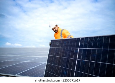 Installing solar power plant as sustainable energy source. Worker placing solar panel on the roof. - Shutterstock ID 2255591619