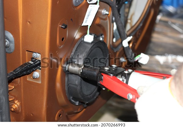 Installing\
the speaker in the car. An auto mechanic installs a car speaker\
from the door using a rivet. The process of working with a rivet\
close-up. A car repairman repairs a car\
door