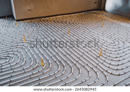 Installing underfloor heating system consisting of plastic pipes fixed on concrete surface flooring