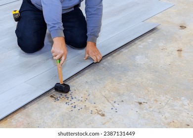 Installing vinyl laminate flooring in new home by construction worker - Shutterstock ID 2387131449