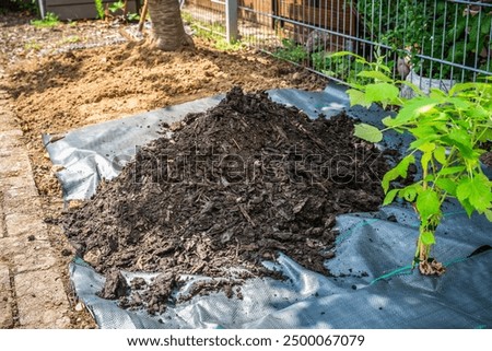 Installing weed control fabric material and bark mulch in a residential garden to control weed spreading