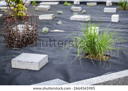 Installing weed control fabric material and bark mulch in a residential garden to control weed spreading