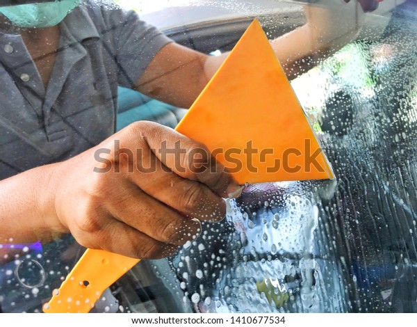 installs tint film for car glass with hairdryer\
and spatula with glare of light.\
