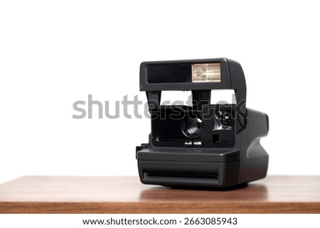 An instant camera instantly develops photos on a wooden table. Vintage camera concept. Photography concept. Space for text.