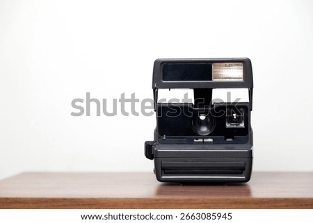 An instant camera instantly develops photos on a wooden table. Vintage camera concept. Photography concept. Space for text.