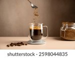 Instant coffee pouring in transparent glass mug, roasted coffee beans
