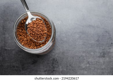 Instant Coffee And Spoon Above Glass Jar On Grey Table, Top View. Space For Text