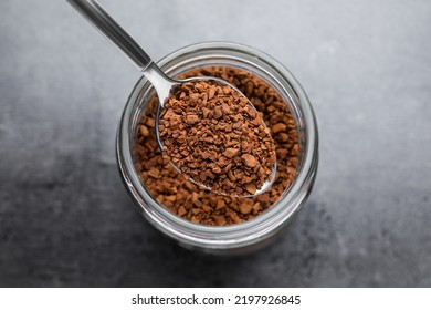 Instant Coffee And Spoon Above Glass Jar On Grey Table, Top View