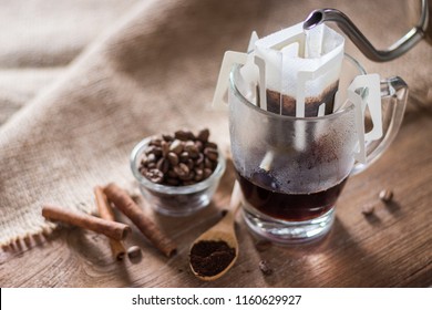 Instant drip coffee using paper type filter with beans and cinnamon on wooden background