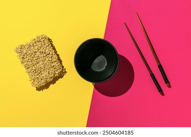 Instant Noodles with Black Bowl and Chopsticks on Vibrant Yellow and Pink Background - Powered by Shutterstock