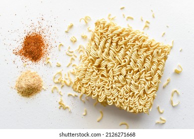 Instant noodles with seasonings on the table.  Uncooked noodles with dried red chilli flakes and ingredients on white.  Flat lay top view food photography.  Food from above concept. - Shutterstock ID 2126271668